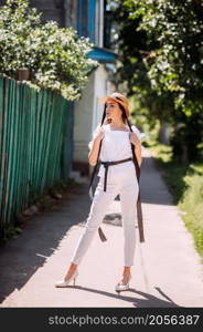 A young girl in a hat on the background of the blooming streets of the city.. A stylish young girl walks through the spring streets 3601.