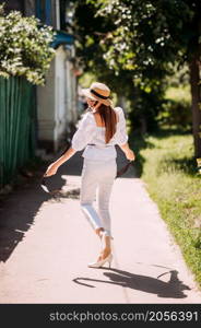 A young girl in a hat on the background of the blooming streets of the city.. A stylish young girl walks through the spring streets 3605.