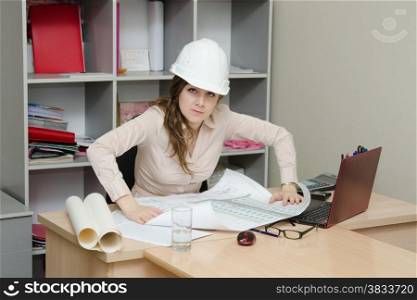 A young girl in a helmet works at his desk in the office
