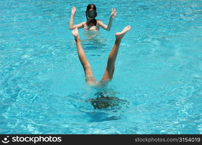 A young girl looking at a man standing upside down in a swimming pool, Moorea, Tahiti, French Polynesia, South Pacific