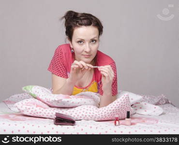 A young girl lying in bed and saws, nails nail files