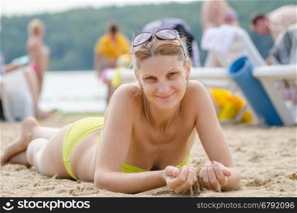 A young girl picked up sand lying on his stomach on the sandy beach