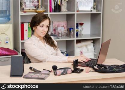 A young girl puts makeup in the office workplace