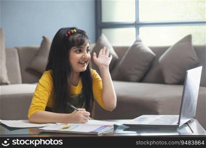 A YOUNG GIRL RAISING HAND TO ANSWER DURING ONLINE CLASS