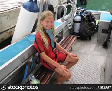 A young girl sitting in a boat with scuba gear, Moorea, Tahiti, French Polynesia, South Pacific