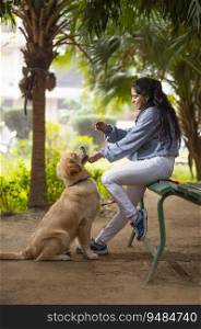 A YOUNG GIRL SITTING ON A BENCH AND PLAYING WITH PET DOG
