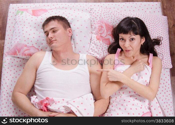 A young girl waking up in the morning sees a stranger guy in bed