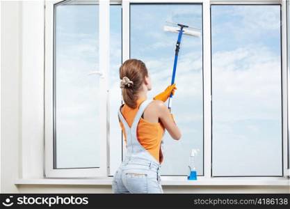 A young girl washes the windows in the apartment