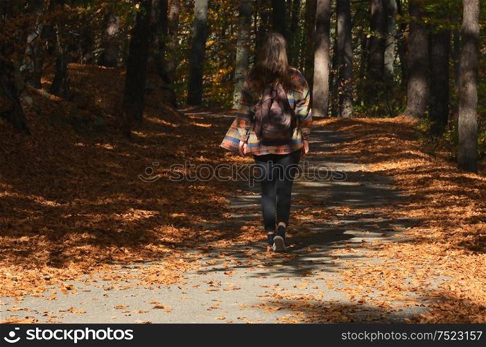 A Young Girl With A Backpack Is Walking Through Autumn Forest