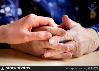 A young hand holding an elderly pair of hands