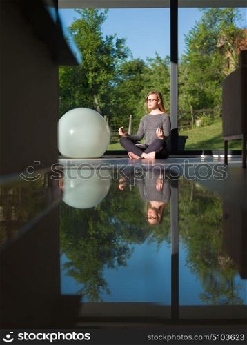 A young handsome woman doing yoga exercises on the floor of her luxury home villa