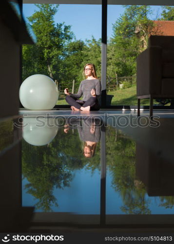 A young handsome woman doing yoga exercises on the floor of her luxury home villa