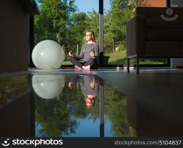 A young handsome woman doing yoga exercises on the floor of her luxury home villa