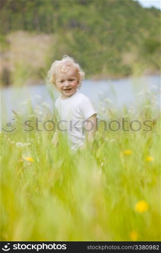 A young happy child walking through tall grass looking at the camera