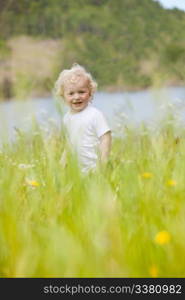 A young happy child walking through tall grass looking at the camera