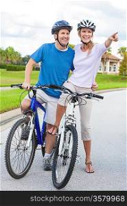 A young happy man and woman couple riding their bicycles or bikes laughing and pointing