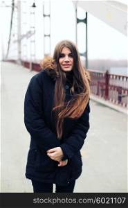 A young hipster woman in the city. View over bridge, outdoors, winter time