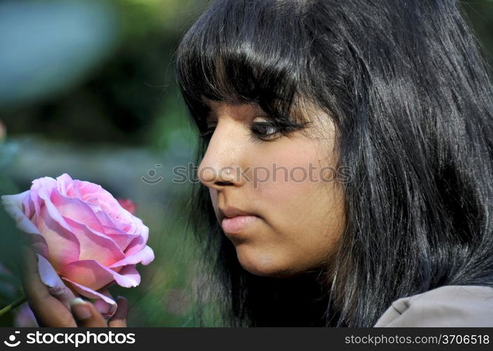 A young Indian woman smelling a flower