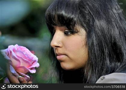 A young Indian woman smelling a flower