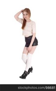 A young lovely brunette woman standing over white background inblack leather shorts and long white socks an high heels