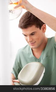 A young male dentist at work adjusting chair and light