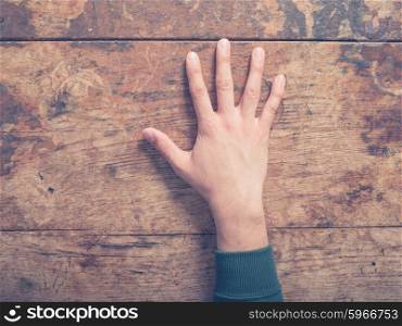 A young male hand on a wooden table