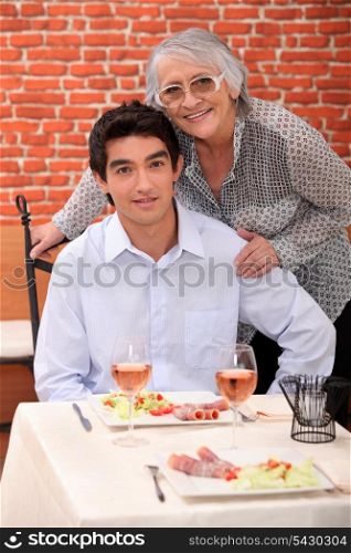 a young man and an old woman at the restaurant posing for the camera