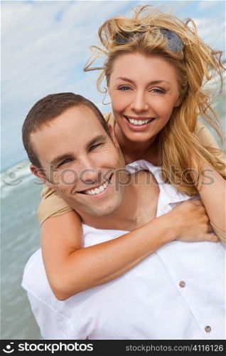 A young man and woman embracing as a romantic couple laughinf and having fun on a beach