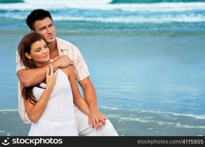 A young man and woman embracing as a romantic couple on a beach