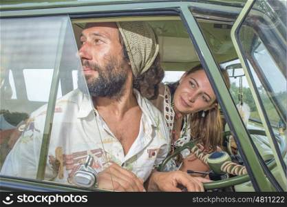 A young man and woman looks out of the window of their camper van as they head of on a journey.