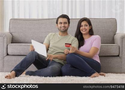 A young man and woman making online payment with credit card and tab in their room.