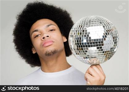 A young man balancing a disco ball