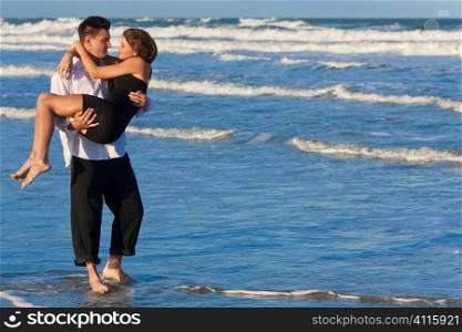 A young man carrying his girlfriend as a romantic couple through the surf on a beautiful beach