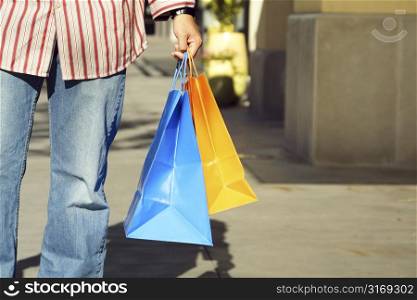 A young man carrying shopping bags at an oudoor mall
