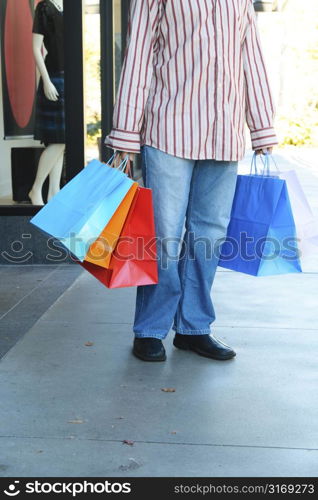 A young man carrying shopping bags at an outdoor mall