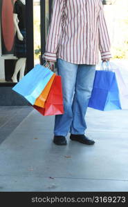 A young man carrying shopping bags at an outdoor mall