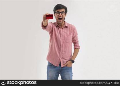 A young man excitedly showing his credit card.