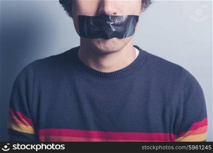 A young man has a big piece of black industrial tape covering his mouth