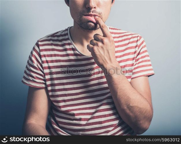 A young man has a toothache and is touching his mouth