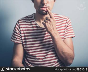 A young man has a toothache and is touching his mouth