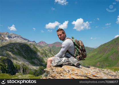a young man hiker sitting on a rock in mountain