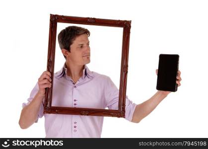 A young man holding up a picture frame, looking trough on his tablet,isolated for white background.