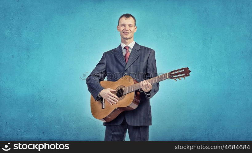 A young man in a black suit playing acoustic guitar. Man play guitar