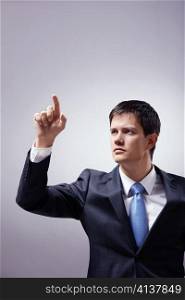 A young man in a suit presses the invisible button on a gray background