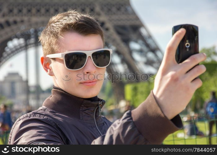 A young man in Paris take a selfie in front of the Eiffel Tower