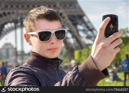 A young man in Paris take a selfie in front of the Eiffel Tower