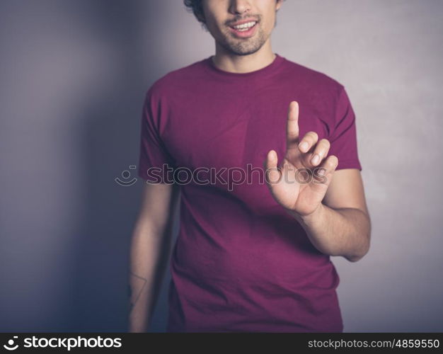 A young man in purple is raising his finger to swipe, push or establish authority