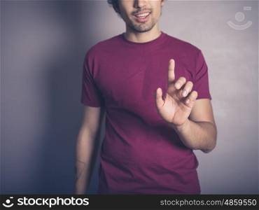 A young man in purple is raising his finger to swipe, push or establish authority