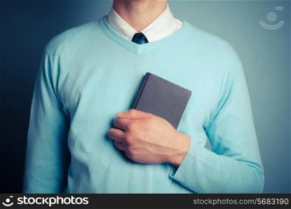 A young man is clutching a small notebook