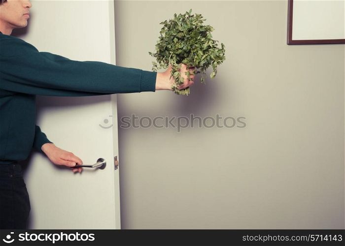 A young man is entering a home and bringing a bunch of parsley